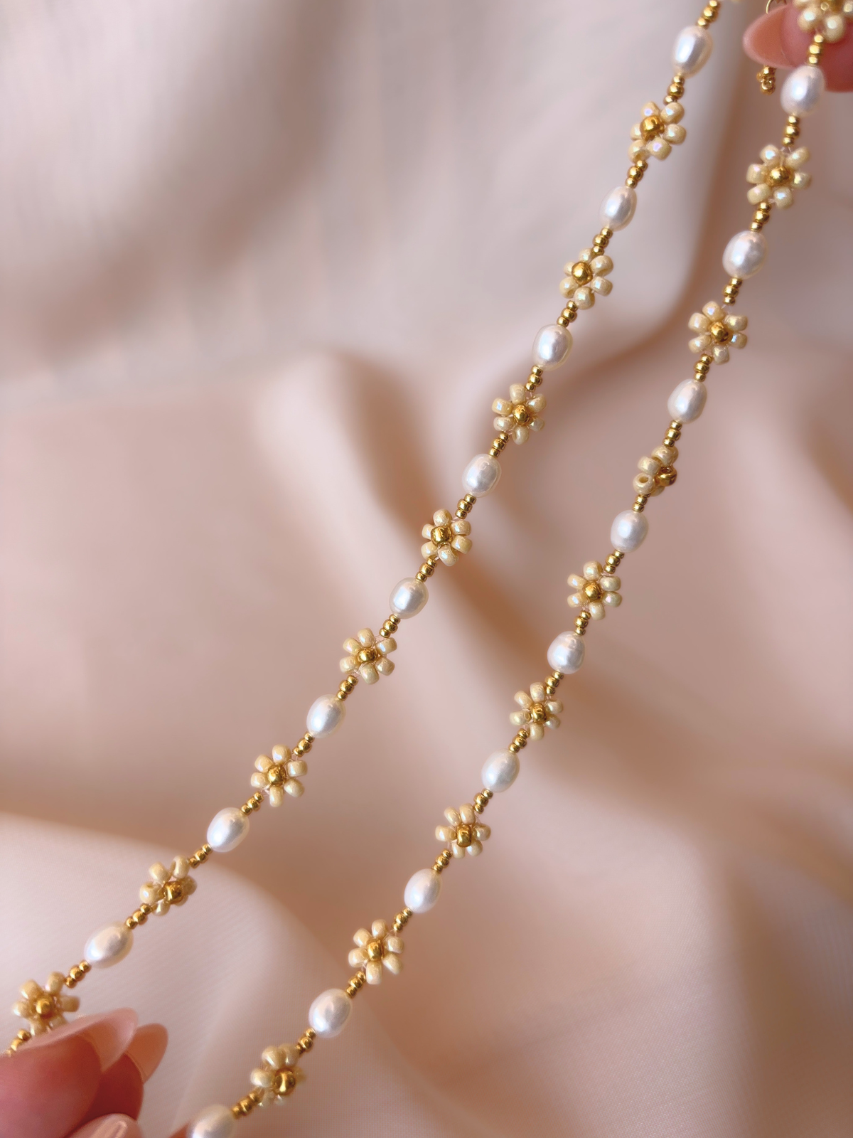 Close up of August Pearl Necklace showcasing the natural luster of white freshwater pearls and premium Japanese seed bead gold daisies.