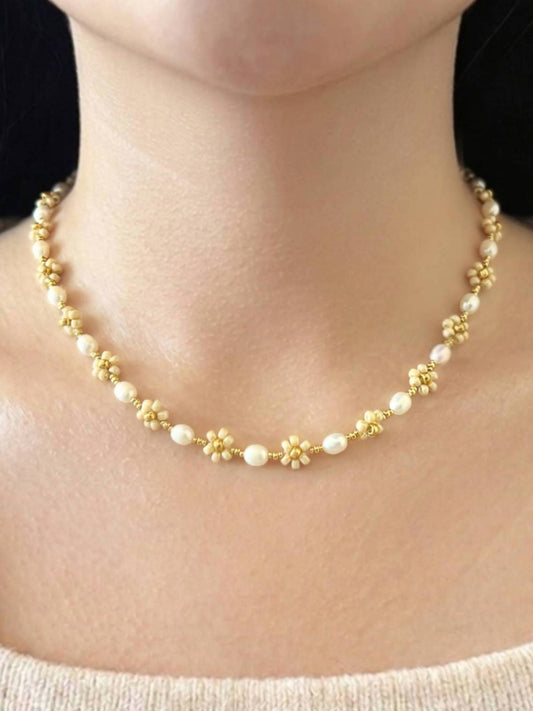 August Pearl Necklace made of white freshwater pearls and premium Japanese seed bead gold daisies, shown worn on a model's neck.