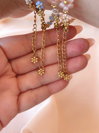 Close up of multiple dangling gold daisy charms and adjustable extender chains on Dear Daisy flower bracelets.