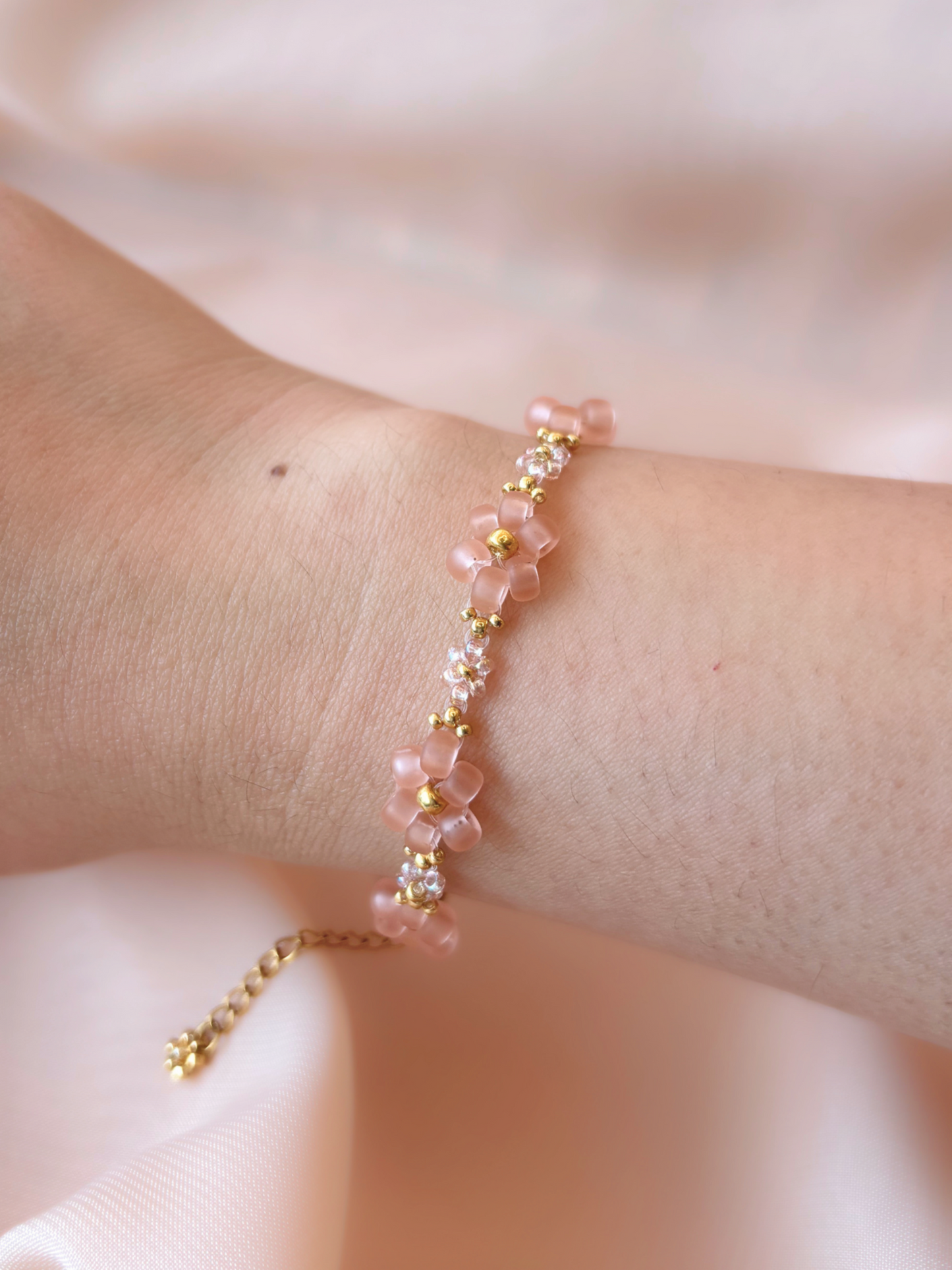 Dear Daisy Bracelet in First Kiss, featuring translucent pink flower beads made of premium Japanese seed beads, shown worn on a wrist.