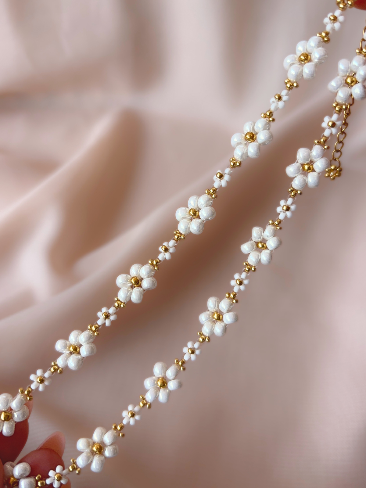 Close up of Dear Daisy Choker in Cloud Nine, showcasing white flower designs made of premium Japanese seed beads.