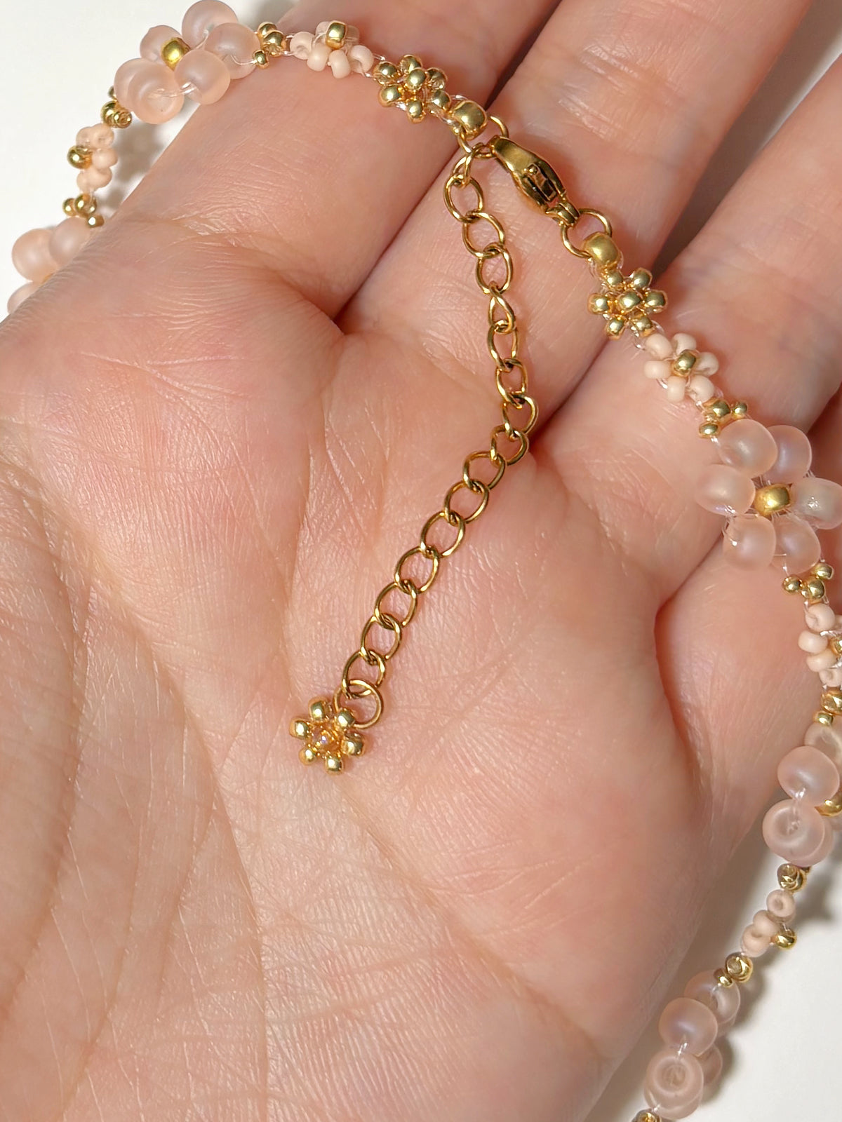 Close up of the dainty dangling gold daisy charm and adjustable extender chain on Dear Daisy choker.