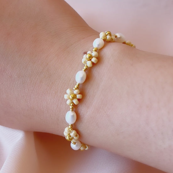 A video showcasing the August Pearl Bracelet worn on a wrist, highlighting the natural luster of freshwater pearls and sparkle of gold seed bead daisies.