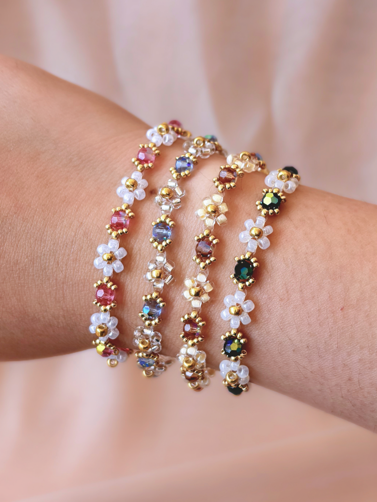 A stack of four Wildflower Coquette flower bracelets in all available colorways, showcasing the premium Japanese seed beads and sparkling Preciosa crystals on a wrist.