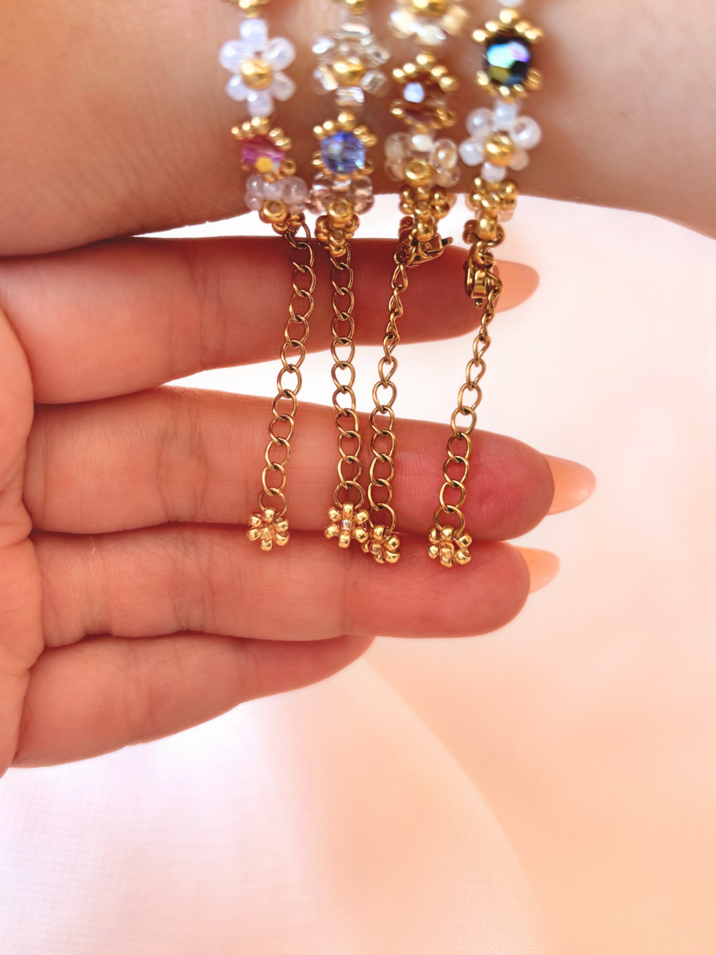 Close up of the dainty dangling gold daisy charm and adjustable extender chain on Wildflower Coquette bracelets.