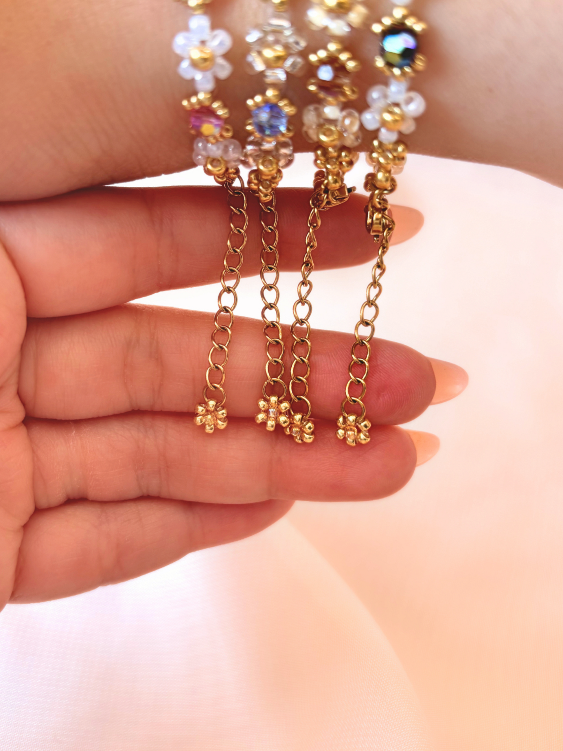 Close up of the dainty dangling gold daisy charm and adjustable extender chain on Wildflower Coquette bracelets.