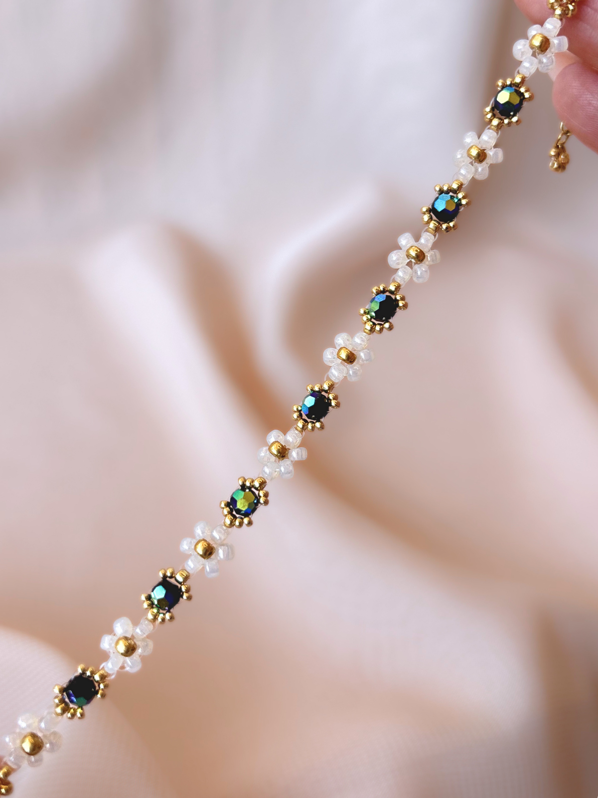 Close up of Wildflower Coquette bracelet in Midnight Rain, showcasing premium Japanese seed bead daisies and black Preciosa crystal AB centers.