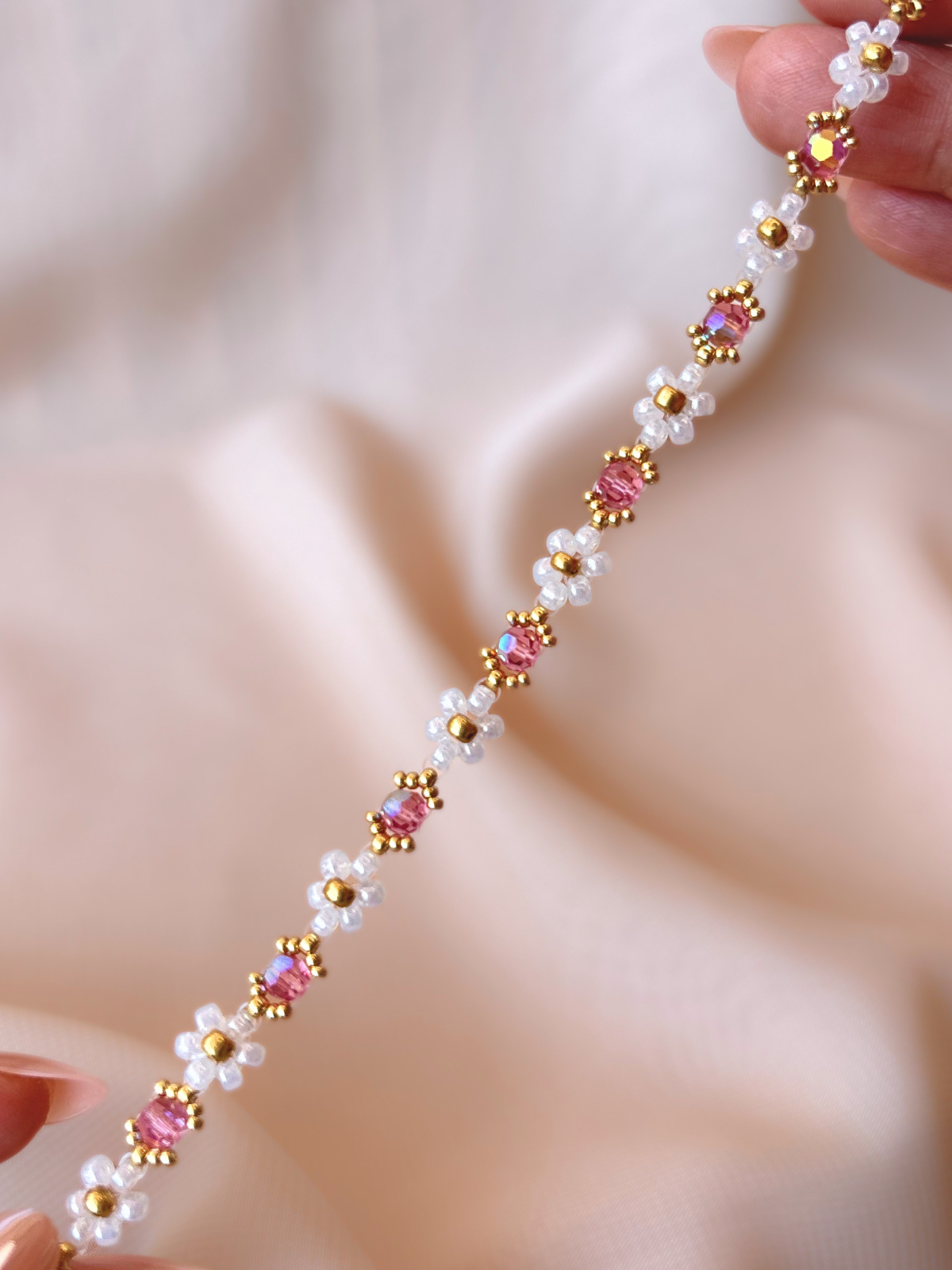Close up of Wildflower Coquette bracelet in Pinky Promise, showcasing premium Japanese seed bead daisies and pink Preciosa crystal AB centers.