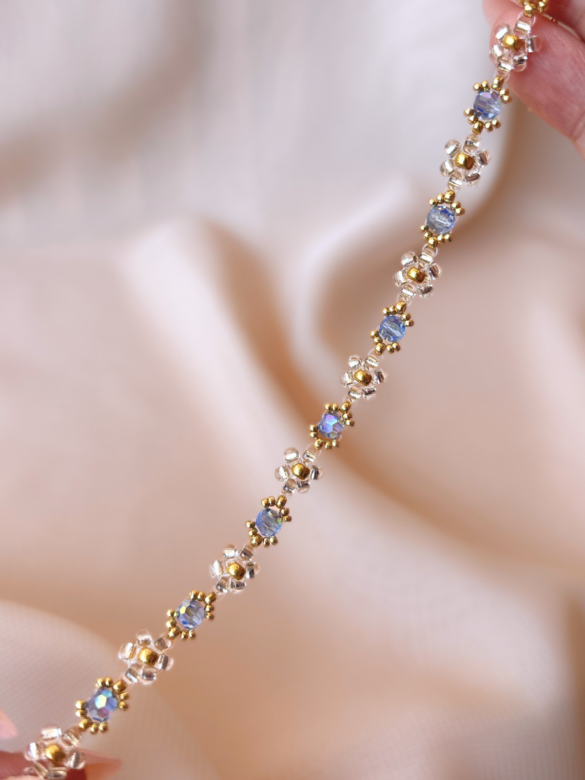 Close up of Wildflower Coquette bracelet in Pixie Dust, showcasing premium Japanese seed bead daisies and blue Preciosa crystal AB centers.