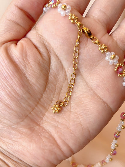 Close up of the dainty dangling gold daisy charm and adjustable extender chain on Wildflower Coquette choker.